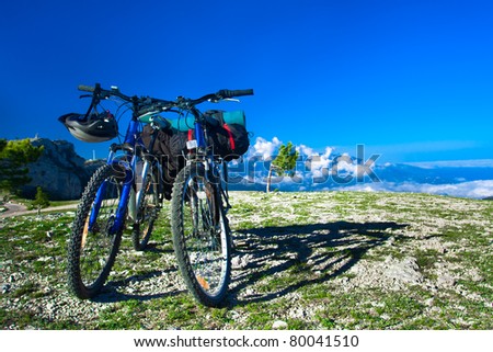 two bikes on the precipice, sky and mountains in the background