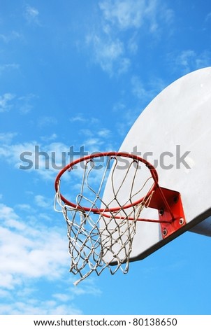 Outdoor basketball hoop with blue sky and clouds