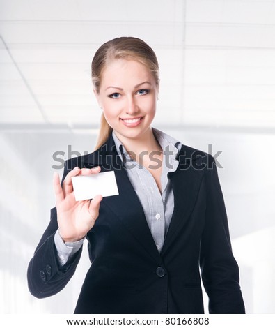 businesswoman in black suit holding blank empty sign. office background