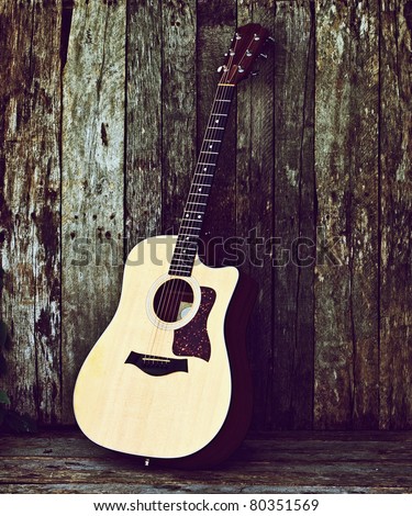 Acoustic guitar on a grunge wood backdrop with copy space.