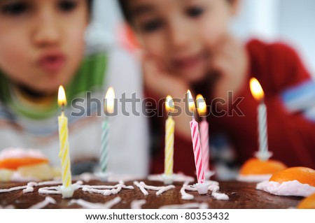 Two little boys blowing candles on cake, happy birthday party