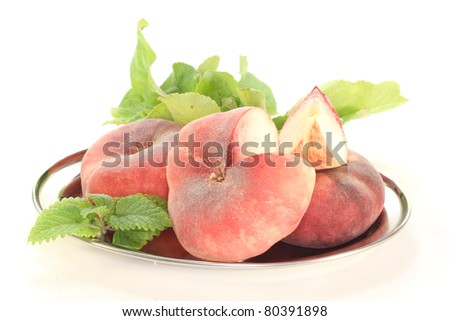 three mountain peaches on a platter with lemon balm on a white background
