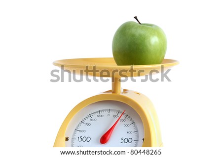 Green apple lying on yellow kitchen scale. Isolated on white background with clipping path