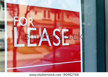 For Lease sign on red in window reflecting street scene