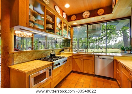 Oak kitchen with tile floor and nature view.