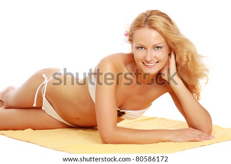 A beautiful smiling woman in a white swimsuit is lying on a yellow towel