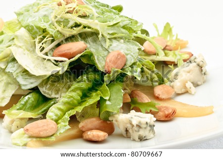 A portion of roquefort cheese salad decorated with arugula and pine nuts on a white plate