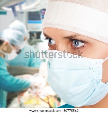 young female surgeon with two doctors on background in operation room