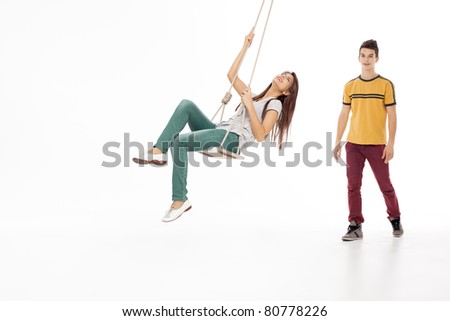 young woman swinging on a swing with handsome man looking