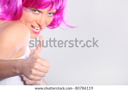 A portrait of a happy young woman showing ok sign over light background. Focus on hand
