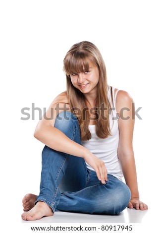 Smiling teenager girl sitting in studio on white background