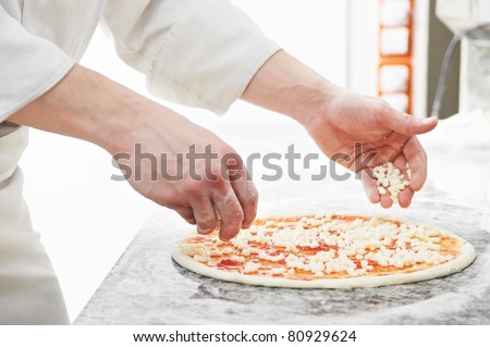 Closeup hand of chef baker in white uniform making pizza at kitchen