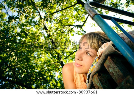 young woman lying on a rusty bed outdoors