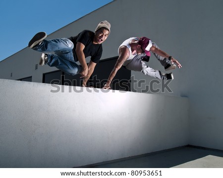 two free-runners jumping over a wall Royalty-Free Stock Photo #80953651