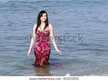 Young smiling woman standing in sea waves