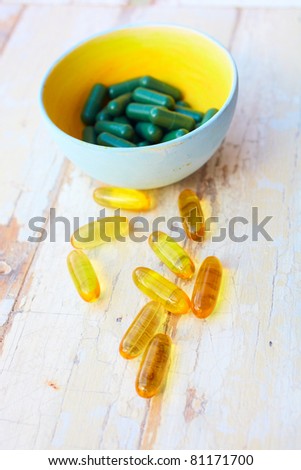 fish oil vitamins capsules and herbal supplement pills on the grunge vintage background - focus on middle yellow pills