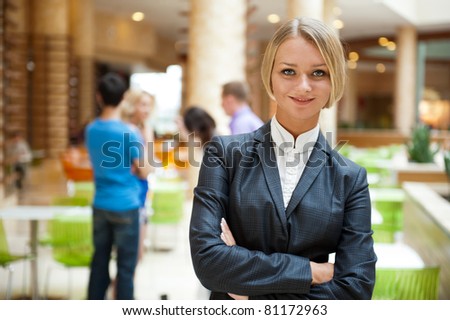  Portrait of a cute business woman with colleagues at the background. Indoors at modern office building center