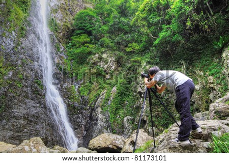 photographer taking photo in front of waterfall