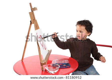 Little boy painting a picture on a canvass standing on an easel