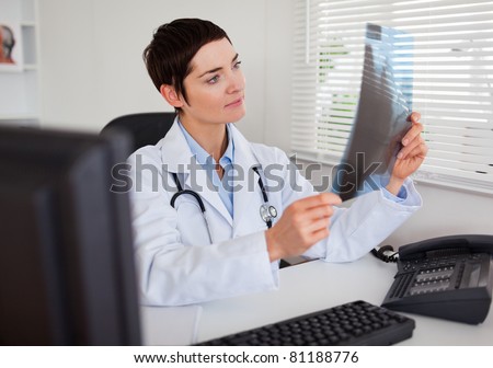 Doctor looking at X-ray in her office