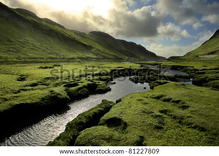 Spring in Scotland Valley: Infectious greens, winding streams, and volatile skies -- all typical of spring in Scotland.  Taken on Isle of Skye, in the Scottish Highlands. Royalty-Free Stock Photo #81227809