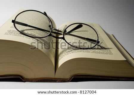 A book and eyeglasses on white background