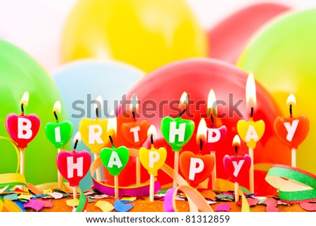 burning happy Birthday candles with balloons and confetti