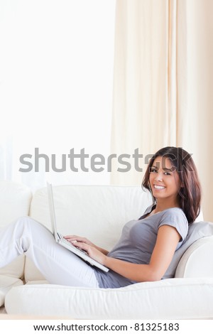 cute woman smiling into camera while sitting on sofa in living room