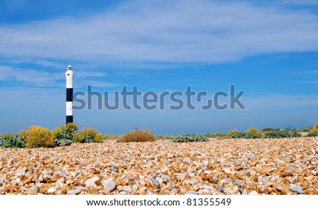a lighthouse on a shingle beach by day