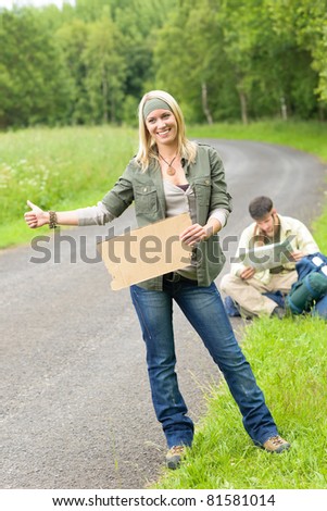 Hitch-hike young couple backpack tramping on asphalt road play guitar