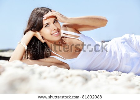 Portrait of beautiful young woman with golden tan resting at beach in summer