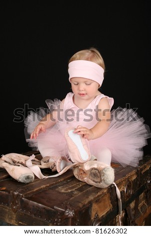 Blond toddler wearing a tutu holding Ballet shoes