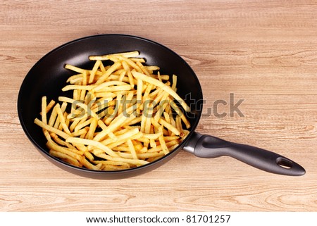 French fries in the pan on a wooden background