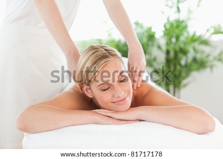 Close up of a smiling woman relaxing on a lounger enjoys a massage in a wellness center