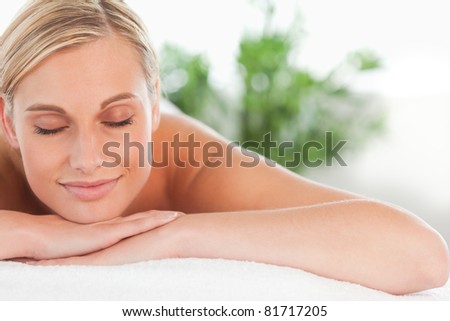 Close up of a blonde smiling woman relaxing on a lounger with eyes closed in a wellness center