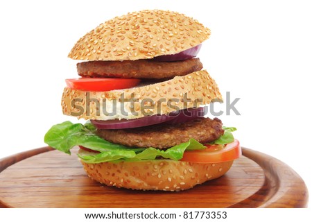 big double roasted hamburger on wooden plate with cutlery isolated  over white background