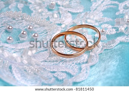 Pair of golden wedding rings over invitation card decorated with lace