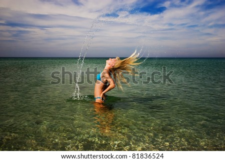 Motion freeze of a blond girl splashing the sea water with her hair
