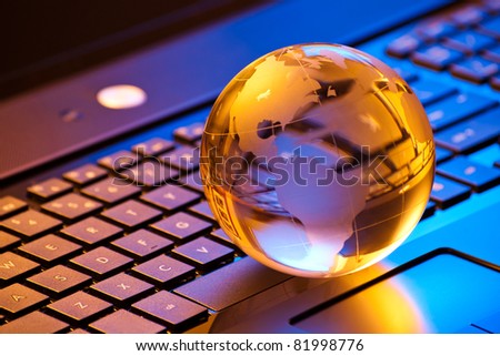global computer business concept with small globe on laptop keyboard in mixed light Royalty-Free Stock Photo #81998776