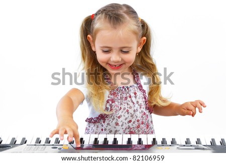 Little happy girl playing on a keyboard instrument.