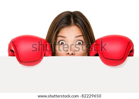 Funny sign woman hiding scared and afraid behind blank empty paper sign board edge wearing boxing gloves. Young Asian business woman isolated on white background.