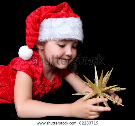 adorable girl in Christmas outfit playing with golden star ornament. isolated