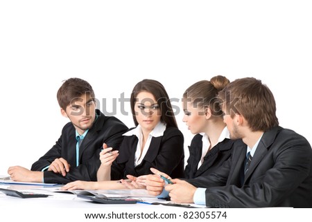 four attractive positive young business people in elegant suits sitting at desk working in team together and discussing the problem, business plan, papers, document, Isolated over white background