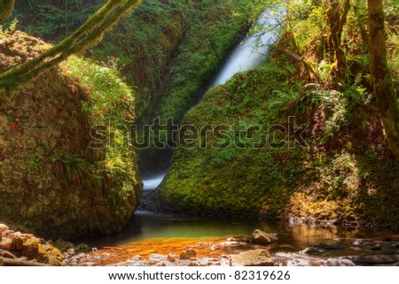 Unique Side View Perspective of Bridal Veil Falls In The Columbia River Gorge Area Of Multnomah County In Oregon.  Unique Lighting Also Highlights Shimmering Of The Misty Spray Off Moss Covered Rocks.