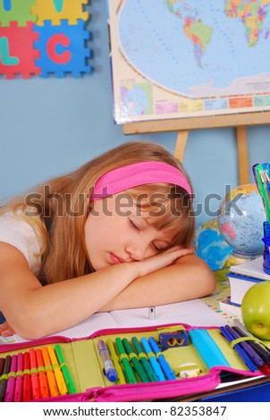 tired schoolgirl sleeping with head on the desk  in the classroom