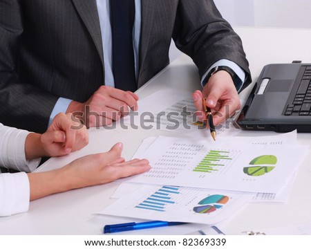 Close-up of business partners hands over papers discussing them