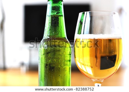 Glass of beer and a bottle against TV-set