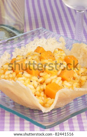Cheese basket filled with risotto and pumpkin over a glass dish.