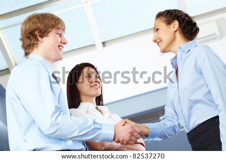 Image of business partners making an agreement with woman standing near by