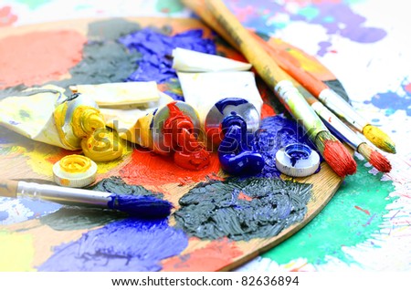 Oily paint brush to the palette on the abstract colored background